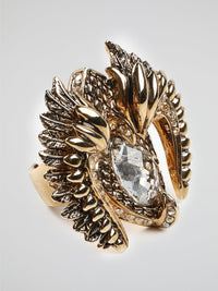 Introducing the Gold Crystal Bird Ring by Roberto Cavalli - an exquisite masterpiece that captures the essence of elegance and grace. Crafted with meticulous attention to detail, this stunning ring features a delicate bird motif adorned with shimmering crystals in a captivating gold setting. Let your style take flight with this exquisite accessory that combines nature's beauty with Roberto Cavalli's signature opulence.